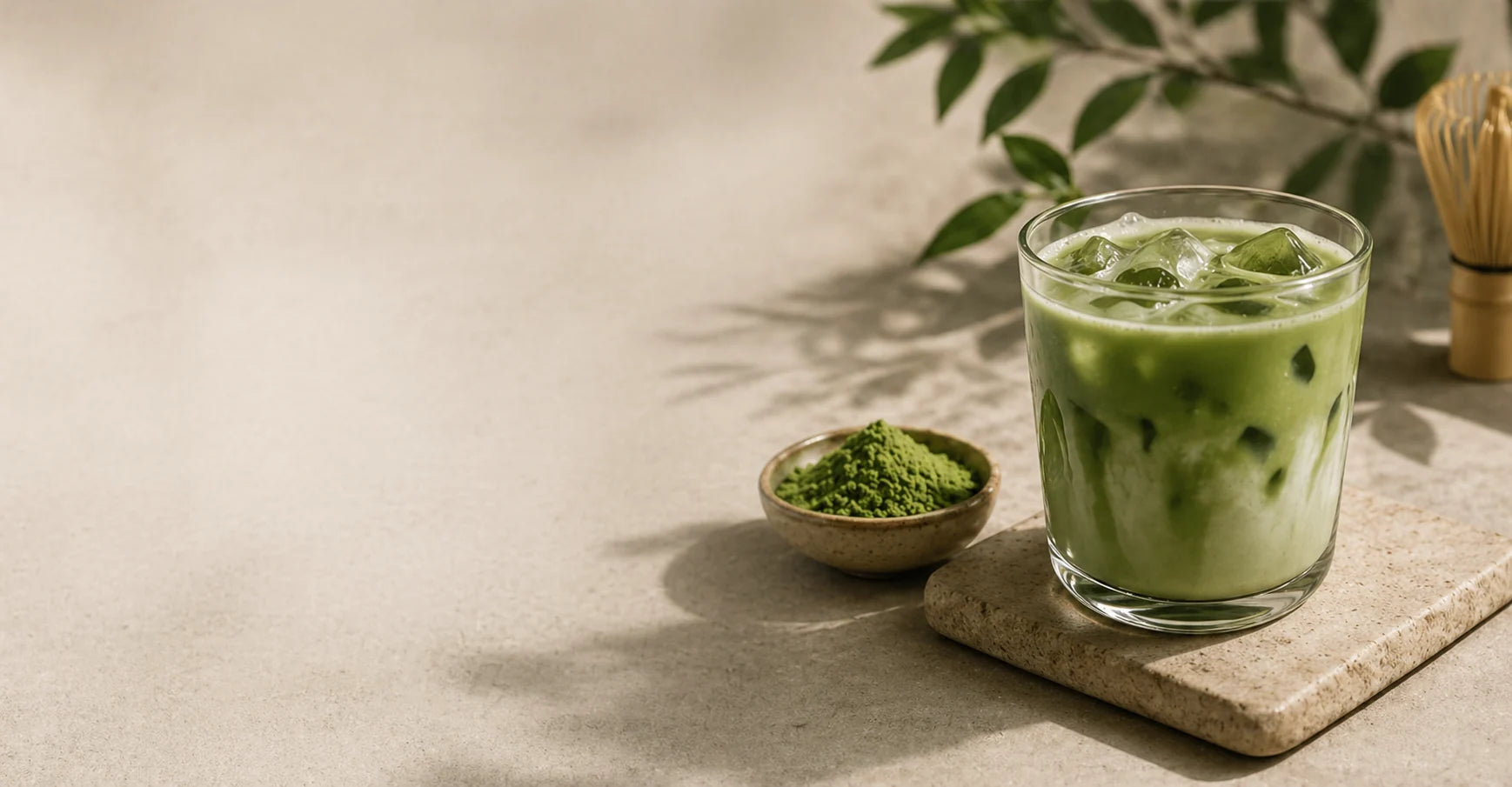 Ledová matcha latte ve sklenici s miskou matcha prášku